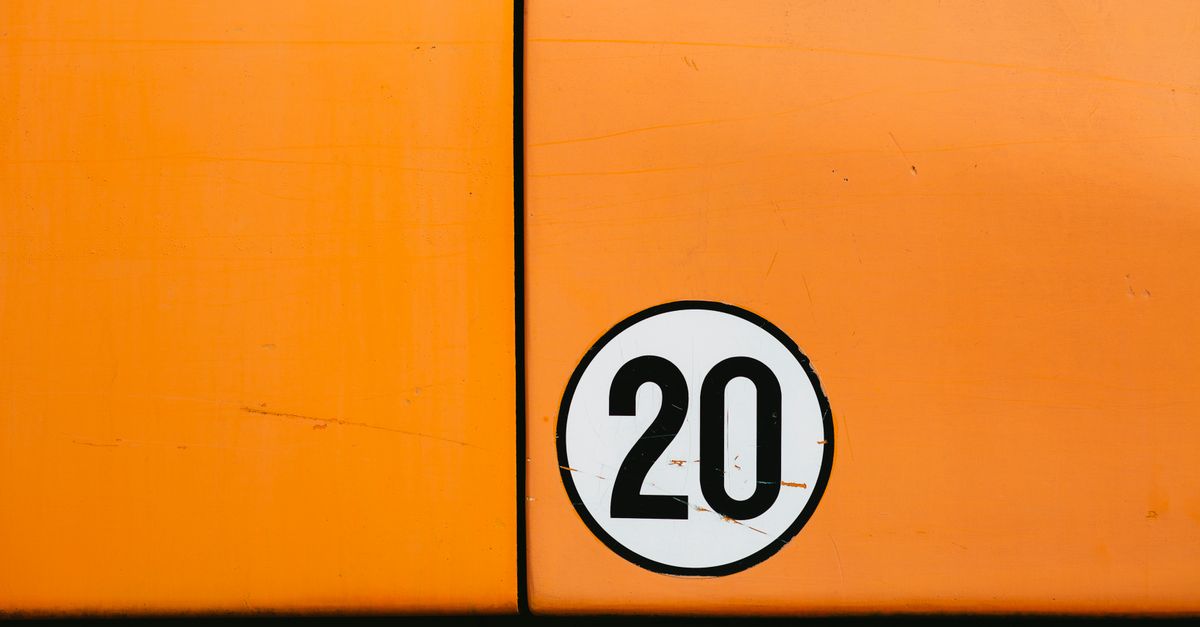 Close-up of a vintage orange vehicle door featuring a bold number 20 in a circle.
