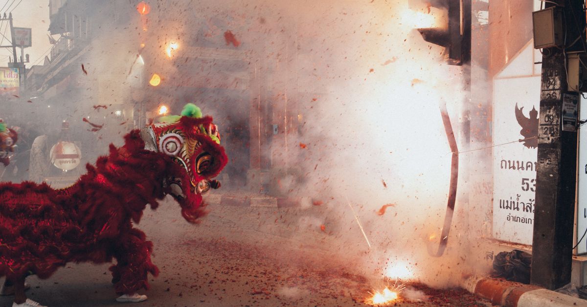 Traditional dragon dance during Chinese New Year in Thailand with fireworks.