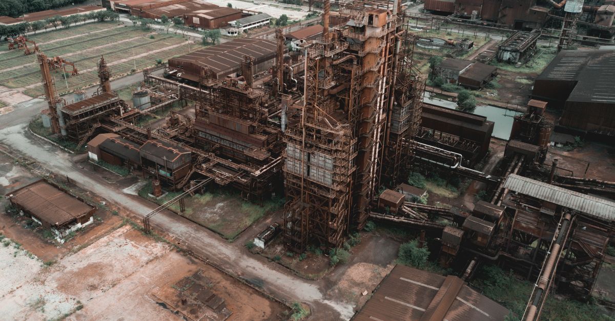 Drone view of aged abandoned industrial factory with rusty metal constructions in suburbs