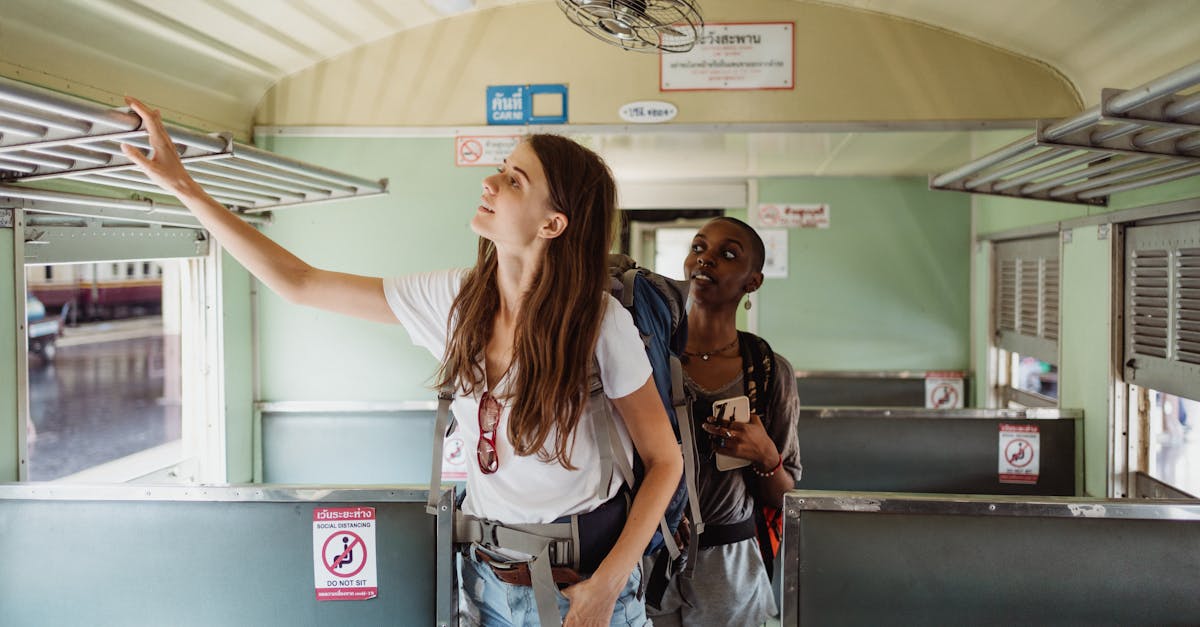 Two women backpackers inside a train carriage setting luggage, enjoying adventure travel.