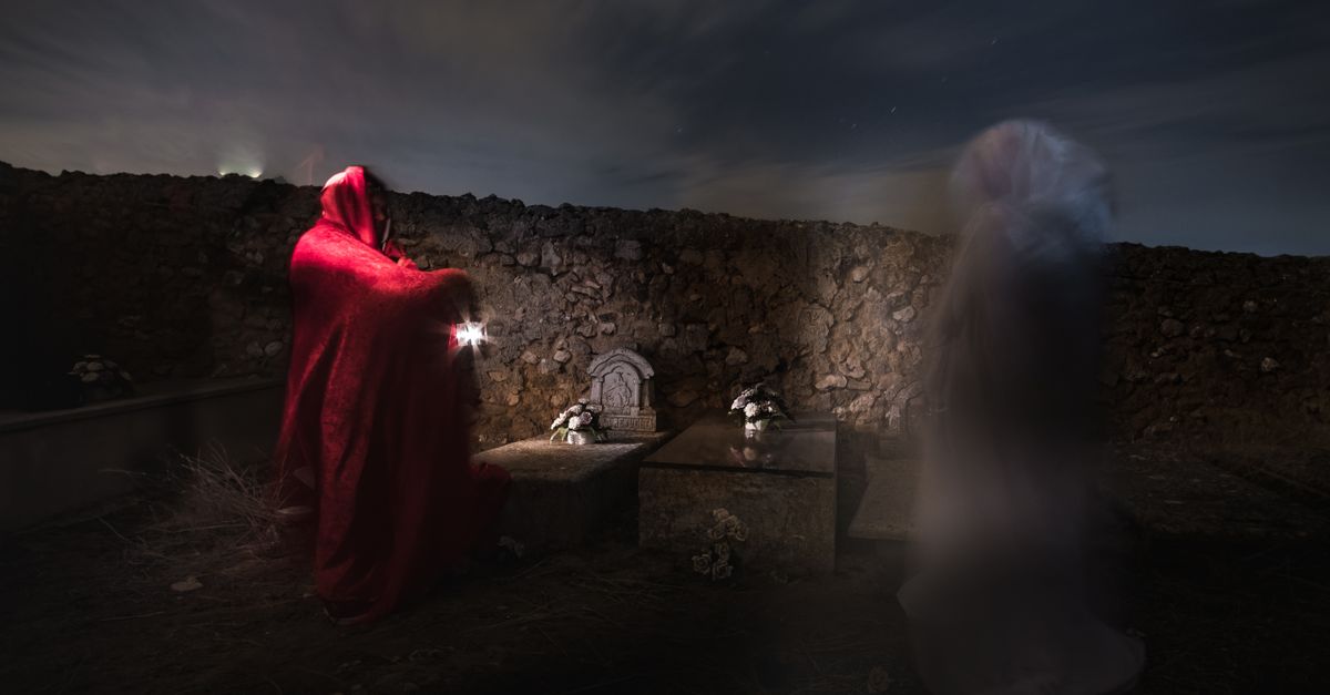 Night scene in a cemetery with a ghostly figure and a person in a red cloak, creating a mysterious atmosphere.