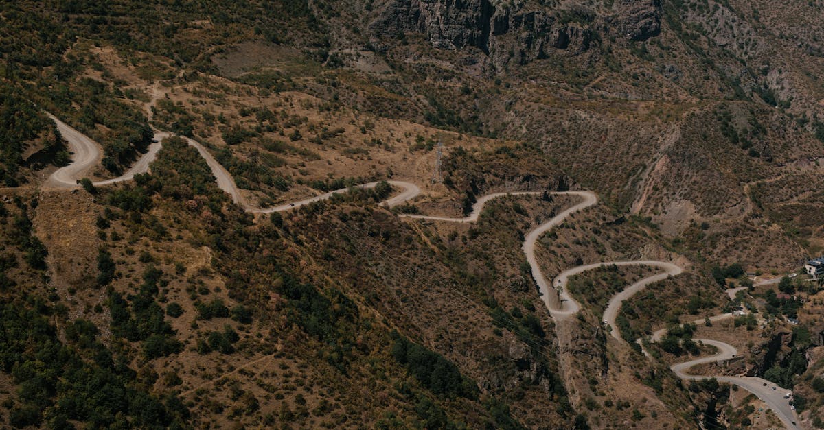 From above of curvy long roadway running on steep slope of mountain in highland