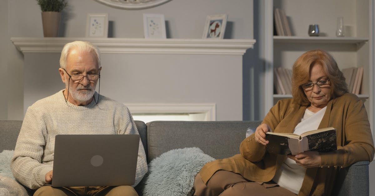 Senior couple enjoying a cozy evening at home, reading and using a laptop.