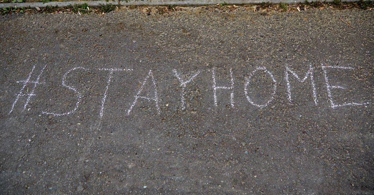 Chalk-written #StayHome message on asphalt during daylight, emphasizing safety and health.