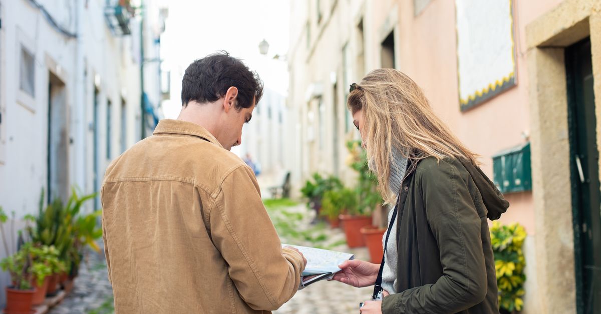Two travelers exploring a charming European street, using a map for navigation.