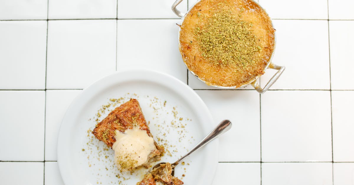 A delectable slice of knafeh with ice cream on a tile background, showcasing its rich texture and flavor.