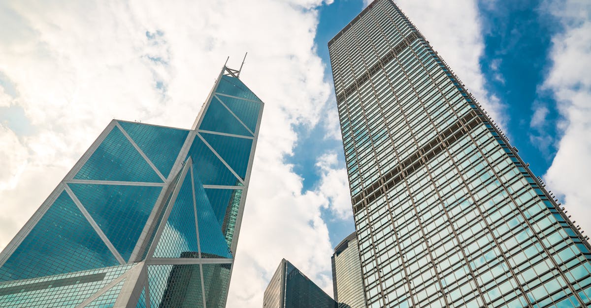 Low angle view of iconic skyscrapers in Hong Kong under a blue sky with clouds.