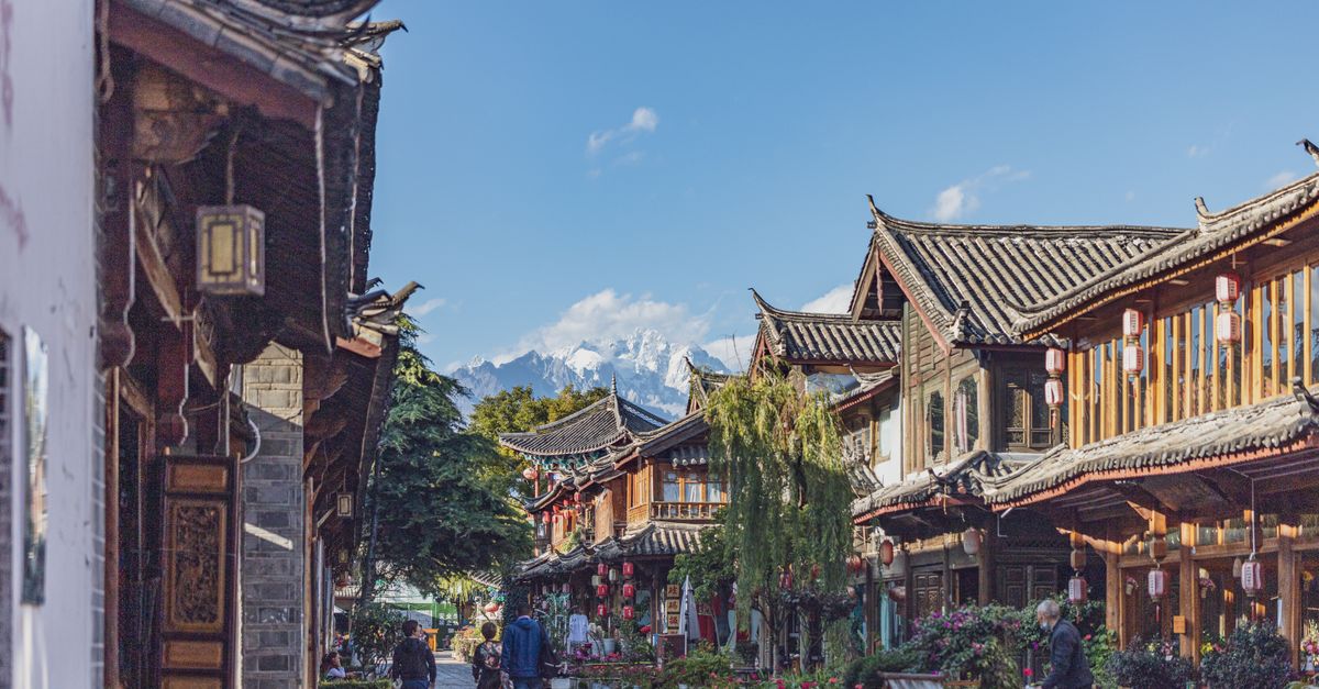 Explore the tranquil charm of an ancient Chinese town street lined with traditional architecture and mountain views.