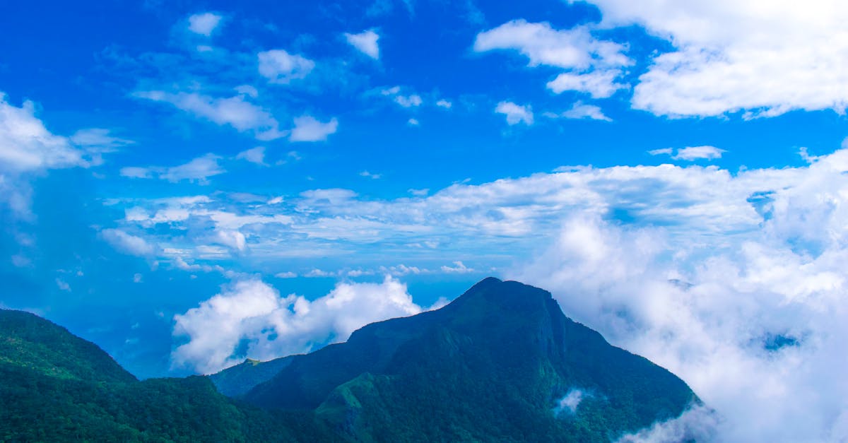 Scenic view of a mountain peak surrounded by clouds with a vibrant blue sky above.