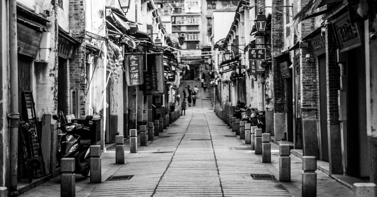 Black and white image of a narrow urban alley, showcasing historic architecture and street elements.