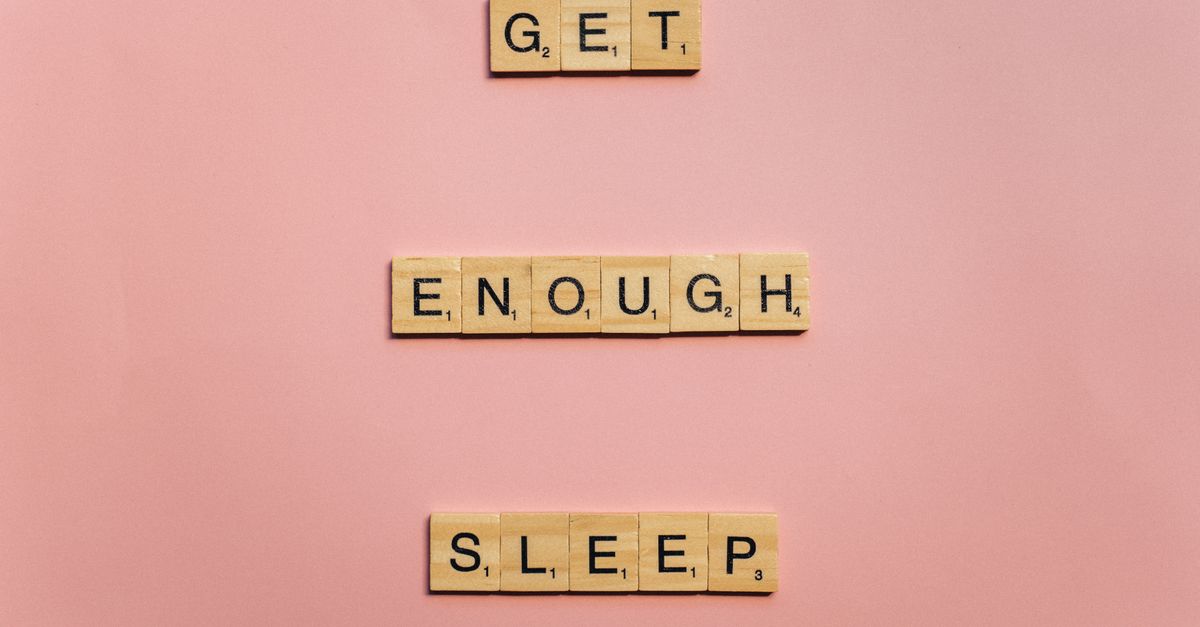 Scrabble tiles on a pink background spelling out 'Get Enough Sleep'. Ideal for wellness and lifestyle themes.