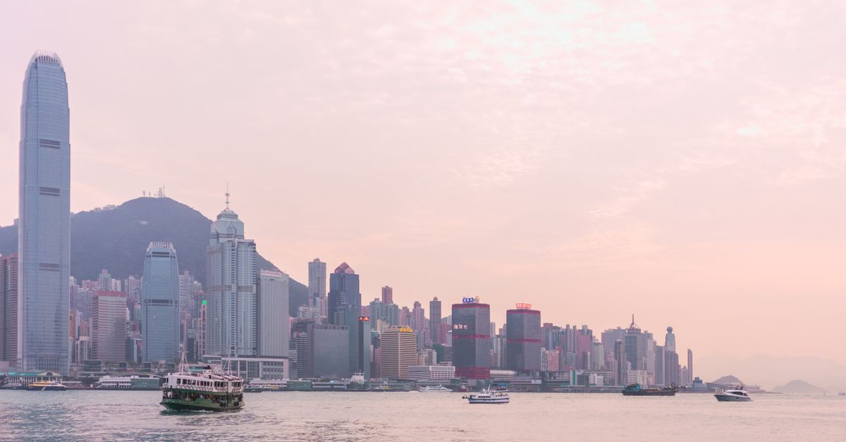 Serene view of the Hong Kong skyline at sunset with boats on Victoria Harbour.