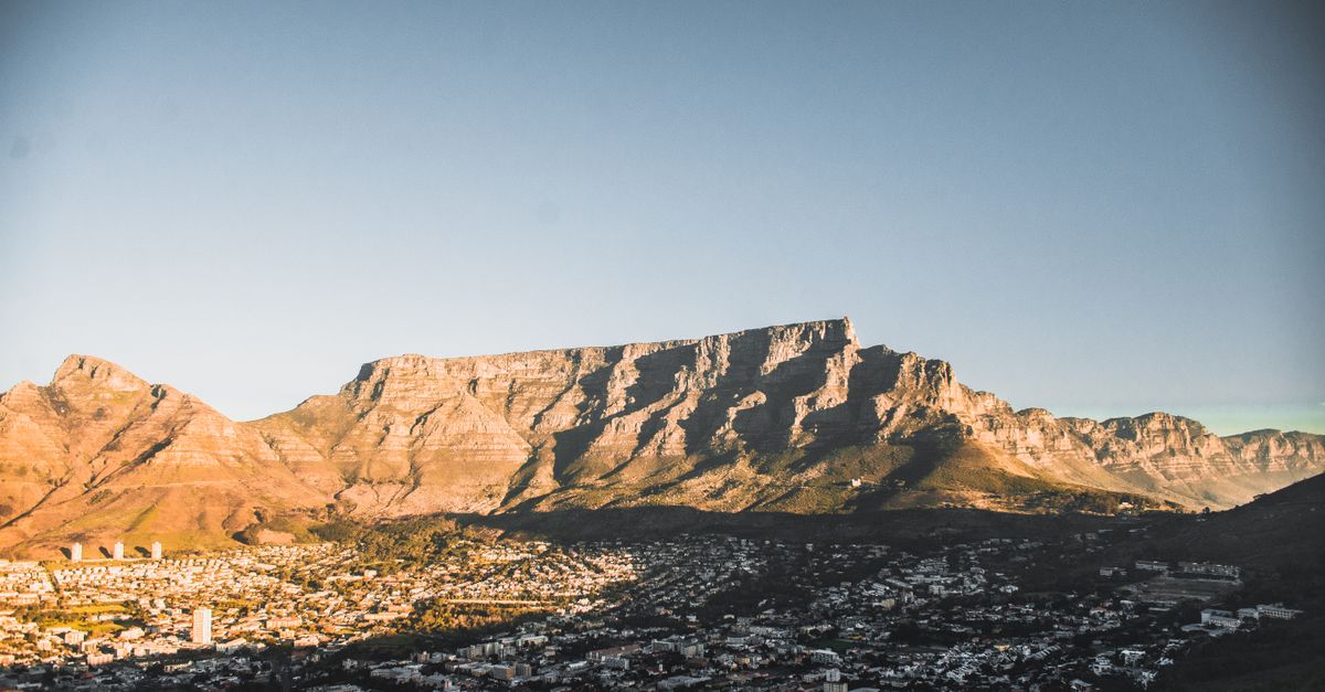 A breathtaking view of Cape Town's cityscape with the iconic Table Mountain in the backdrop during sunset.