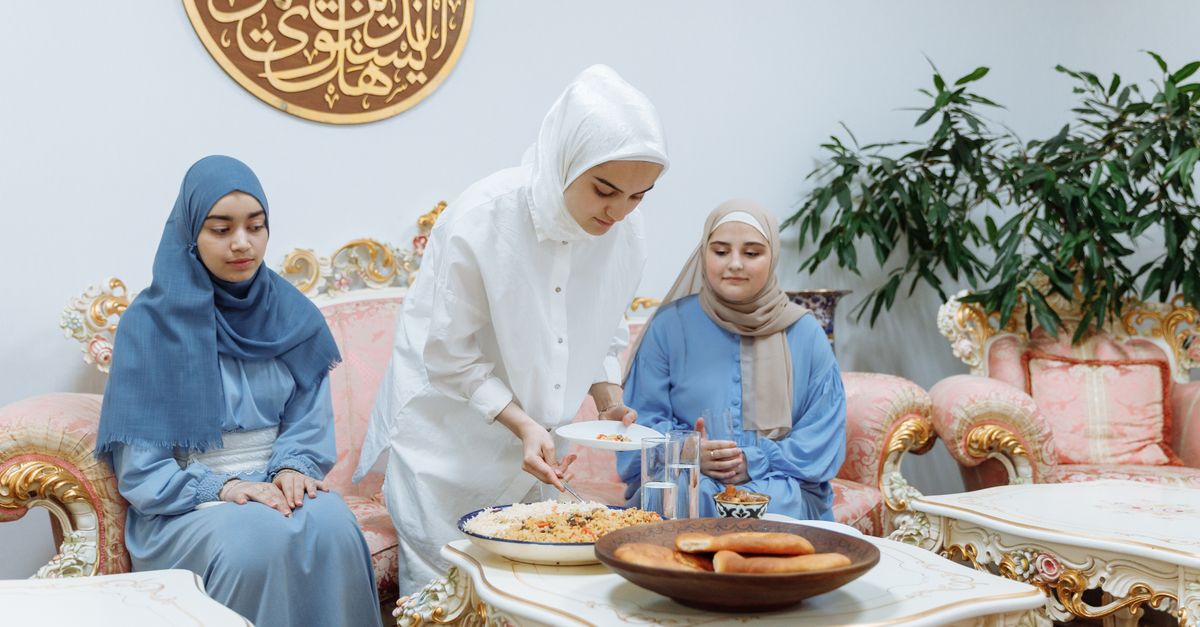 Muslim women preparing and enjoying iftar meal during Ramadan indoors.