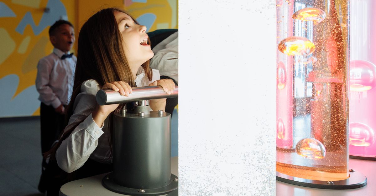 Children engage with interactive science exhibit featuring colorful liquids and lights.